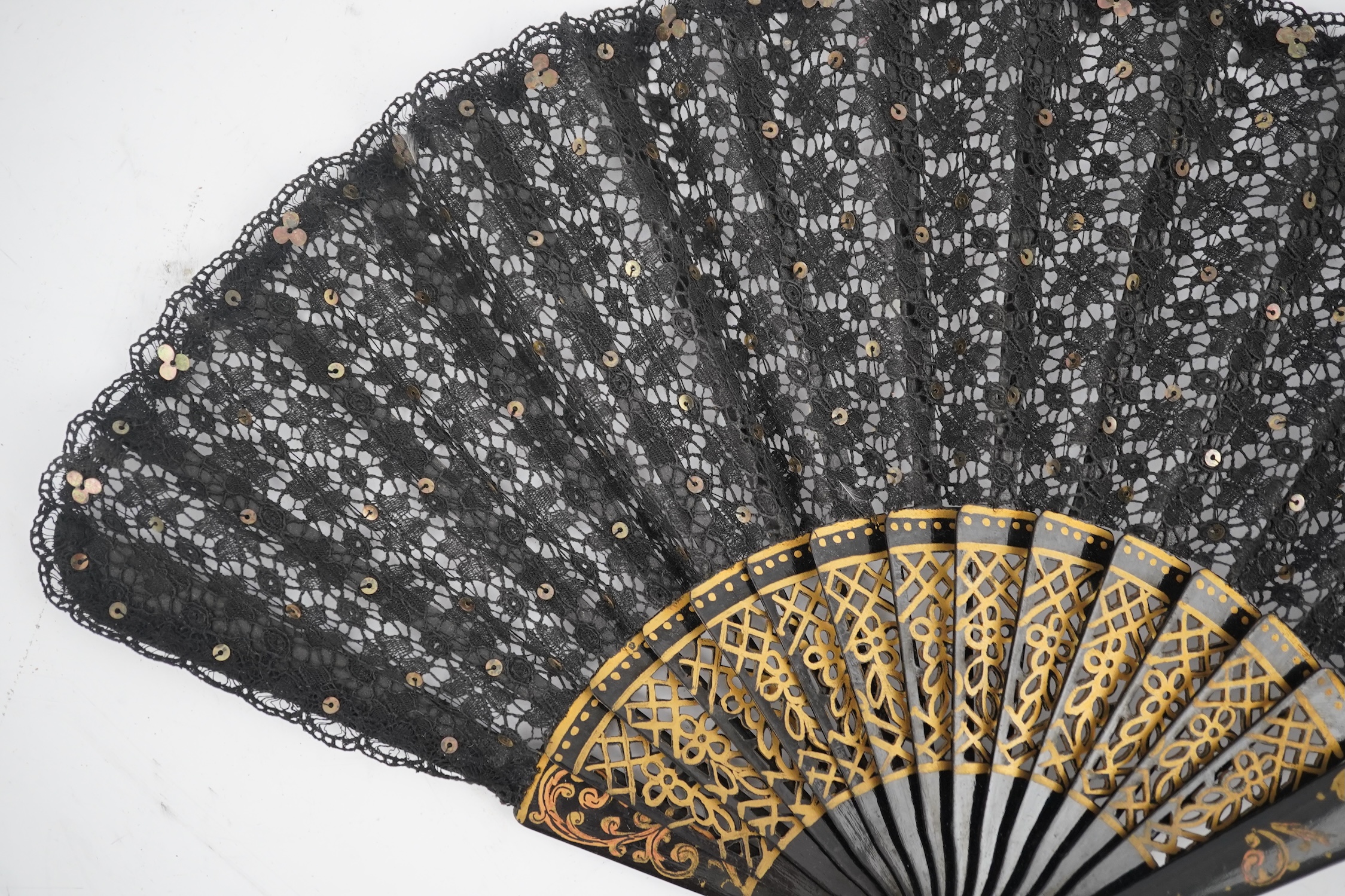 Three novelty fans with a mixed Brussels lace fan and black lace fan, a small language of love in flowers fan, a paper windmill advertising French Café fan, a carved cream Bakelite fan, a black and gilt, lace and sequin